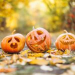 Three pumpkin jack-o-lanterns outside on ground